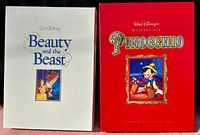Front view of two oversized deluxe edition VHS box sets: Walt Disney's Beauty and the Beast in white and Pinocchio in red.