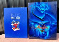 Front view of two deluxe edition VHS sets for Fantasia and Aladdin showing the oversized collector's boxes with distinctive cover art.