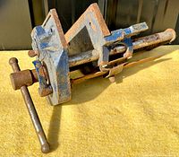 Side view of woodworking vise showing overall length, screw handle, and mounted jaws