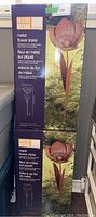 Two boxed metal flower stakes from Inside Outside Garden series displayed one on top of the other showing brand and product details on packaging.