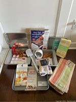 Full view of the lot showing KitchenAid pans, towel sets, dishcloths, spatulas, cookie cutters, and oven pads