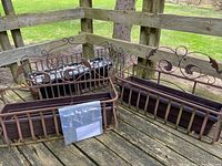 View of three metal balcony planters arranged on wooden deck railing showing rust-colored finish and decorative scrollwork.