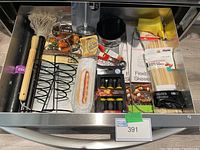 Photo showing assortment of barbecue tools including mop brush, skewers, beer can chicken roaster, and corn holders.