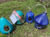 Four ceramic bird feeders with two turquoise and two blue pieces with rope hangers, placed on grass.