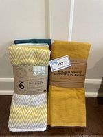 Two sets of kitchen towels side by side in their packaging, showing the variety of colors and the label.