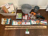 Wide view of entire craft lot contents spread on floor including markers, pens, rulers, baskets, glue tool, tape and notebooks.