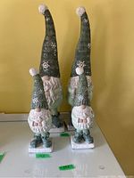 Four winter garden gnomes in two sizes with tall green hats, white beards, and snowflake detailing.