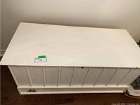 Closed front view of white painted cedar chest with beadboard panel detailing