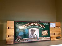 Wooden slatted case with a vintage product label showing a man playing horseshoes and product details.