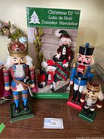 Front view of three nutcrackers and boxed set of Christmas elves with lot number label displayed.