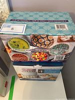 Photo of two boxed sets - one containing six stoneware bowls and another containing four microwavable bowls with lids, all new and boxed.