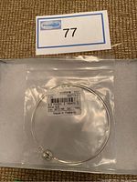 Sterling silver Pandora bracelet in original plastic bag with label visible, lying on a white cushion inside a box.