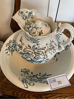 Full view of wash basin with jug and lid inside showing floral blue-green decoration and typical shape