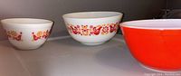 Three vintage Pyrex mixing bowls lined up showing different sizes and pattern on white glass.