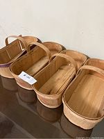 Four wooden fruit baskets lined up side by side, showing handles and general shape