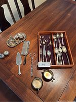 Table view showing the full assortment of silver plated and sterling silver flatware, salt and pepper shakers, serving utensils and trays.