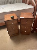 Front and top view showing two matching wood bedside tables with 3 drawers each and a tape measure on top for scale.
