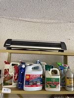 Front view of various yard and cleaning chemicals on shelf including Home Defense Max, 30 Seconds, Moss Killer, Fantastik, and Clorox bottles.