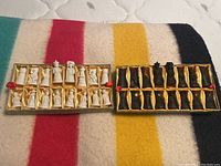 White and black chess pieces arranged inside their respective storage boxes on a colorful striped blanket.