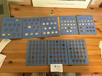 Full view of blue cardboard coin holders with Canadian quarters, dimes, nickels, and pennies arranged on a wooden surface.