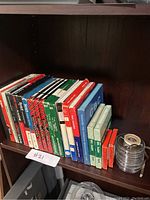 View of shelf with various branded vintage film reel and tape boxes standing upright lined up side by side.