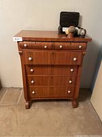 Front view of wooden highboy dresser showing six drawers and white ceramic knobs