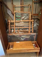 Overview of wooden loom frame components stacked behind a weaving bench