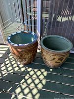 Two large outdoor plant pots placed side by side on a deck showing top and side views