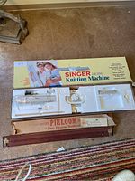 Photo of the Singer LK100 knitting machine in styrofoam and box with Pikloom loom below.
