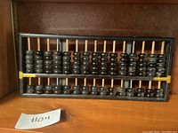 Front view of the wooden Chinese abacus showing the black beads and division by center bar.