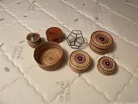 Top view and arrangement of all seven small decorative items on a mattress surface showing miniature baskets, wooden boxes, and geometric decor.