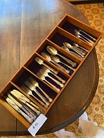 Overall view displaying compartments of silverware organized in a wooden tray, showing the quantity and variety of the silverware.