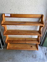 Front view of the wooden wall shelf showing all four shelves and natural wood finish.