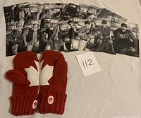 Photo showing the 10 black-and-white Vancouver Canucks cards laid out in a row with the pair of red knit mittens featuring large white maple leaves and Olympic patches.