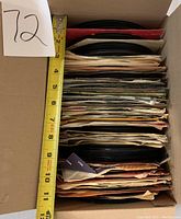 Box showing stacked vintage 45 RPM records measuring about 8 inches in height in cardboard box.