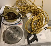 Black & Decker circular saw, two saw blades, hand saw, and extension cord displayed together
