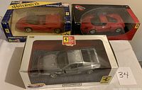 Three 1:18 scale Ferrari model cars displayed in their packaging showing front and top views.