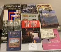 Collection of 11 hardcover books laid out on a surface, titles visible, arranged in two images showing various Canadian-themed books and other subjects.