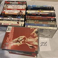Stack of assorted movie and music DVDs showing titles including Napoleon Dynamite, Meet the Parents, Saving Face, Transformeres, and The Devil Wears Prada