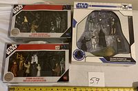 Photo showing two unopened Star Wars Limited Edition Keychain Collector's Cases with multiple character keychains visible through the windows of the packaging, and one Star Wars Villains Keychain Tin in its unopened box.