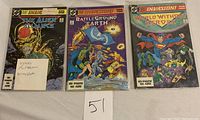 Three comic books laid flat showing front covers: The Alien Alliance, Battleground Earth, and World Without Heroes. Small card notes Todd McFarlane autograph on first book.