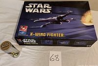 Photo of Star Wars X-Wing Fighter model kit box and Leia wrist watch tin next to bid number.
