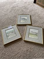 Photos of three framed prints by Pierre Pages, laid on carpet showing gold metal frames and grey mats