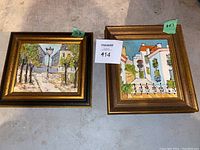 Photo of two framed paintings side by side on floor, one 7x6 inches and one 6x7 inches, with visible wooden frames and impressionistic street scenes