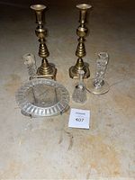 Overview of all items: two metal candle holders, two crystal candle holders, crystal bell, and crystal plate with metal stand on floor.