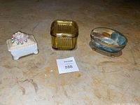 Three dishes: white ceramic flower jewelry dish, yellow glass candy dish, oval stone jewelry dish