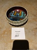 Ceramic bowl viewed from an angle showing the abstract multicolored interior and textured outer side.