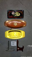 Full lot view of three decorative platters and two stands, showing colors, shapes and materials.