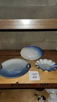 Three porcelain plates featuring a seagull design in blue and white with one plate stand
