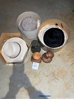 Three women's sun hats together in boxes and hat containers on floor, showing the hats and some of the hat stands.